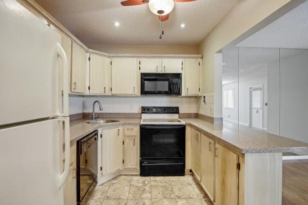 kitchen with kitchen peninsula, a textured ceiling, white appliances, and sink