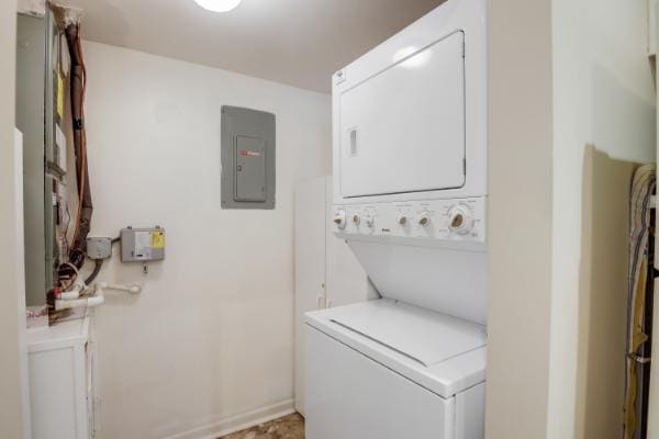 laundry area featuring stacked washer / drying machine and electric panel