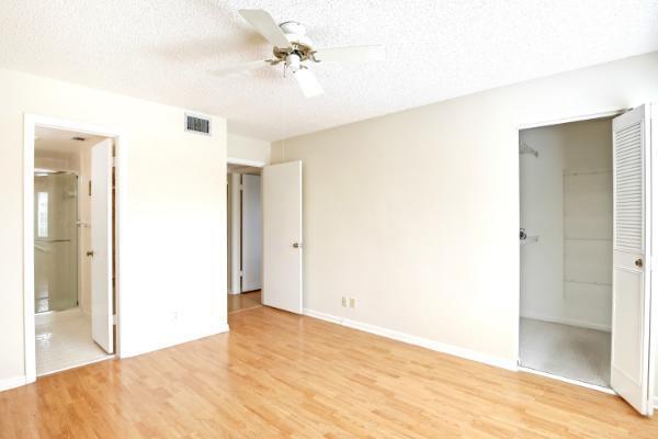 433 Pine Glen Ln Unit A2, Greenacres, FL 33463 - unfurnished bedroom featuring light wood-type flooring, a spacious closet, a textured ceiling, a closet, and ensuite bathroom