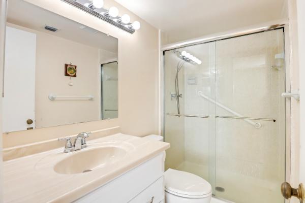 bathroom featuring a shower with door, vanity, and toilet