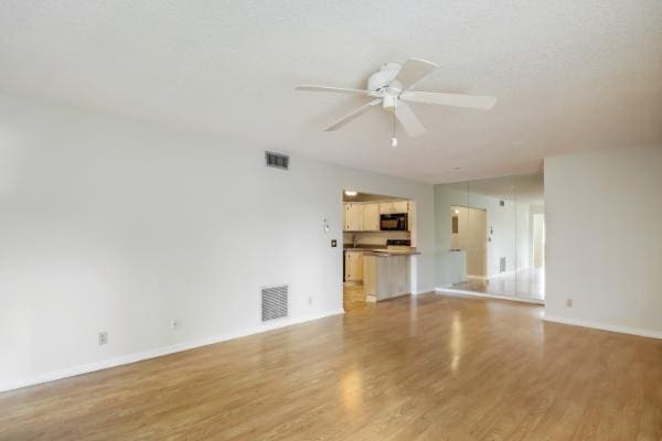 unfurnished living room with ceiling fan and light hardwood / wood-style floors