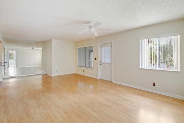 unfurnished living room featuring ceiling fan, light hardwood / wood-style floors, and a textured ceiling