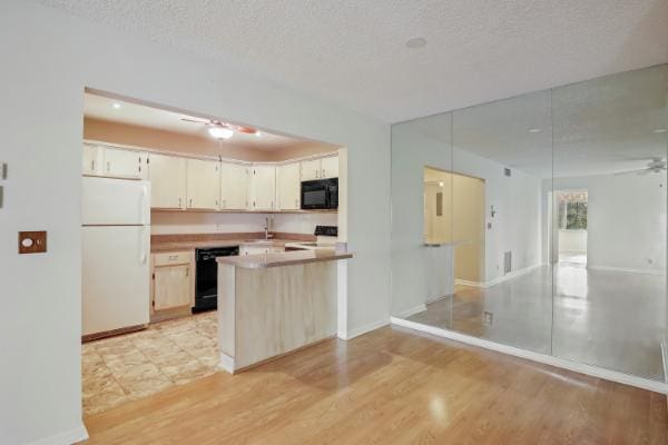 kitchen with ceiling fan, light hardwood / wood-style flooring, kitchen peninsula, a textured ceiling, and black appliances