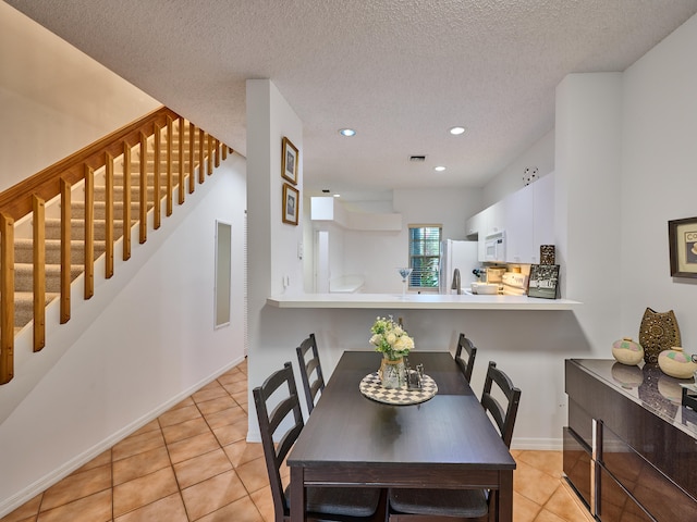 tiled dining area with a textured ceiling