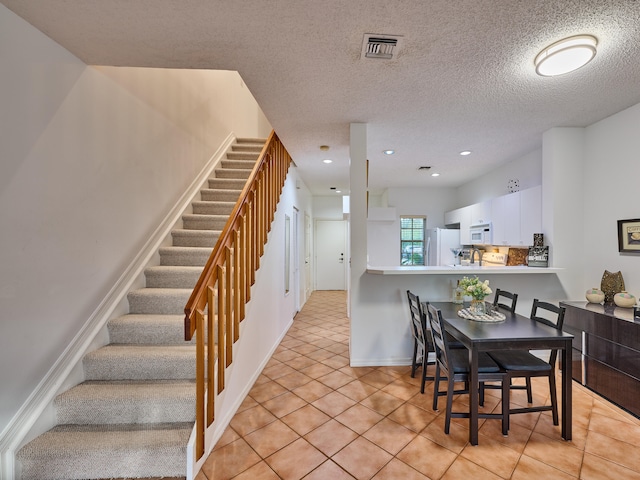 tiled dining space featuring a textured ceiling