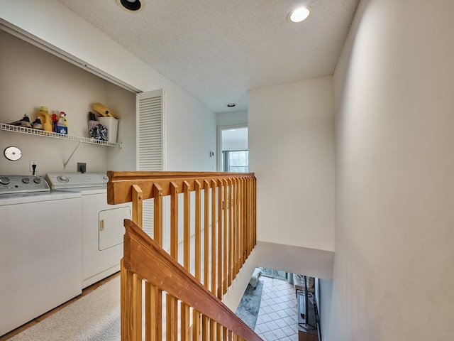 interior space with tile patterned floors, washing machine and dryer, and a textured ceiling