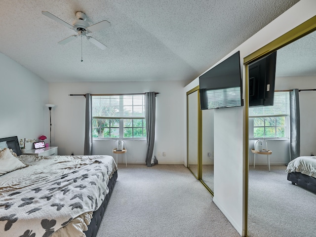 bedroom with light carpet, a textured ceiling, multiple windows, and ceiling fan