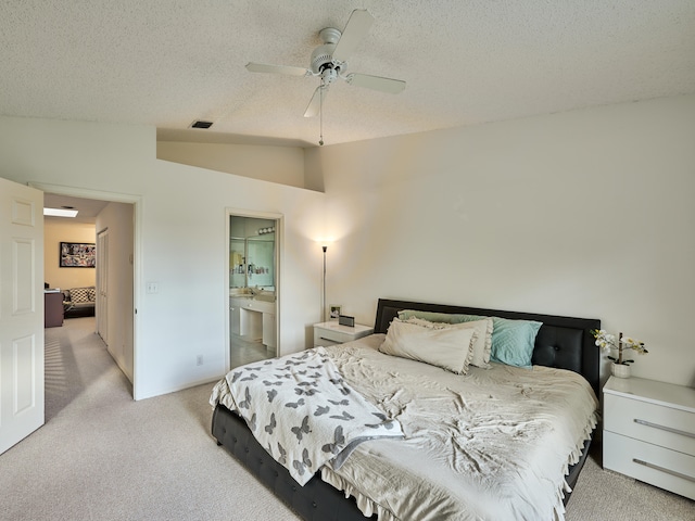 bedroom with connected bathroom, ceiling fan, a textured ceiling, vaulted ceiling, and light carpet