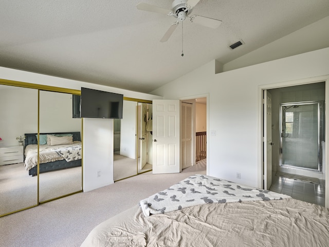 bedroom with ceiling fan, a textured ceiling, vaulted ceiling, carpet, and two closets