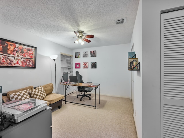 home office with a textured ceiling, light colored carpet, and ceiling fan