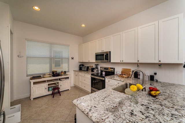 kitchen featuring light stone counters, stainless steel appliances, sink, light tile patterned floors, and white cabinetry