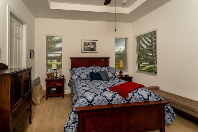 carpeted bedroom featuring ceiling fan, a raised ceiling, and a textured ceiling