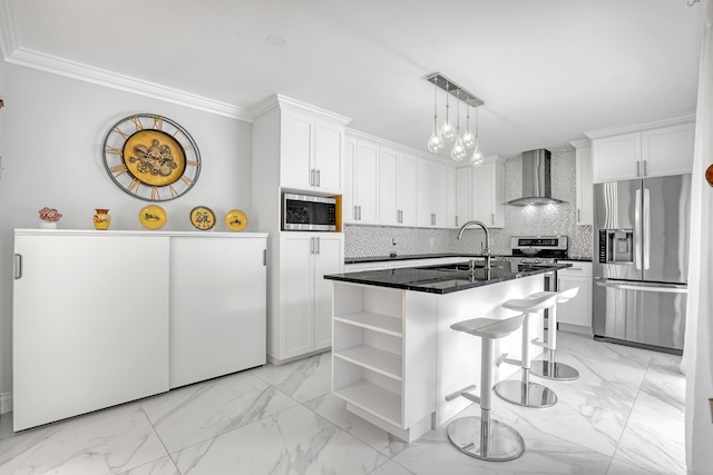 kitchen with wall chimney exhaust hood, stainless steel appliances, an island with sink, decorative backsplash, and white cabinets