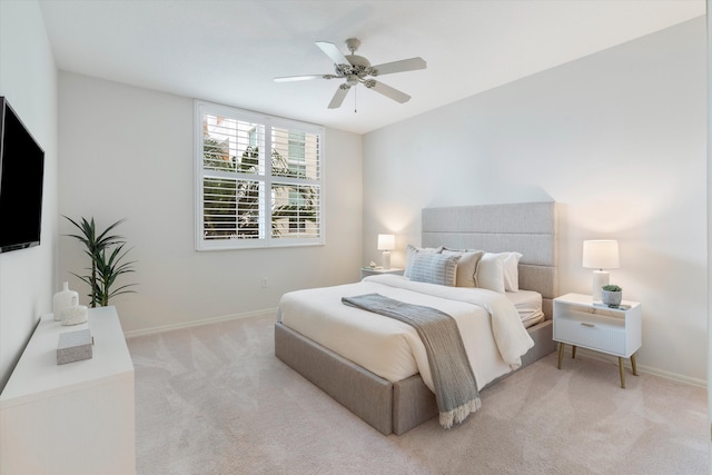 bedroom with a ceiling fan, light carpet, and baseboards