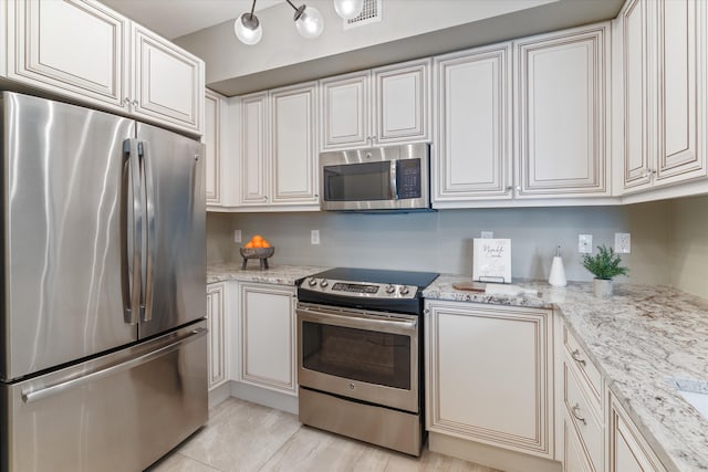 kitchen featuring white cabinets, stainless steel appliances, visible vents, and light stone countertops