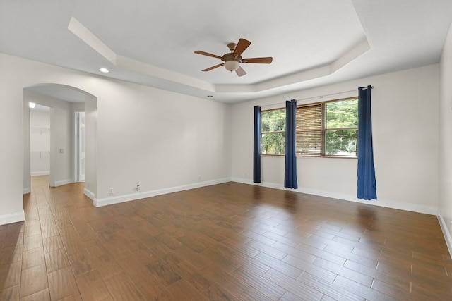 unfurnished room with dark hardwood / wood-style floors, ceiling fan, and a tray ceiling