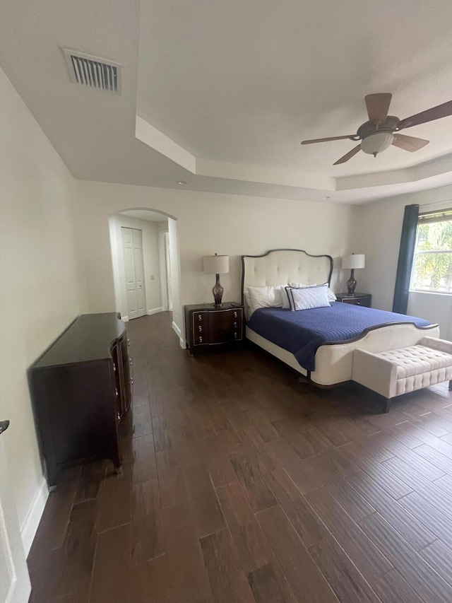 unfurnished room featuring a tray ceiling, ceiling fan, and dark hardwood / wood-style floors