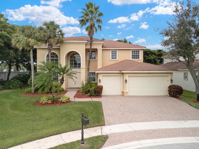 mediterranean / spanish home featuring a front yard and a garage