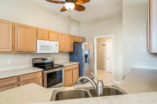 kitchen featuring sink, vaulted ceiling, ceiling fan, appliances with stainless steel finishes, and light tile patterned flooring