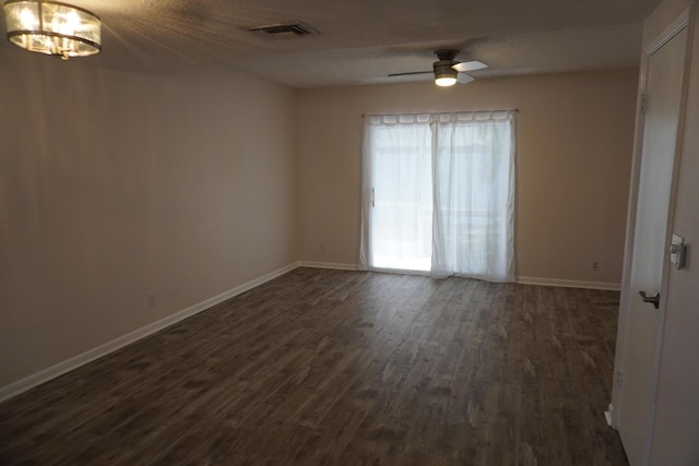 spare room featuring a textured ceiling, dark wood-type flooring, and ceiling fan with notable chandelier