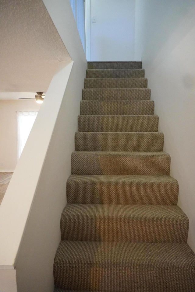 stairs featuring ceiling fan