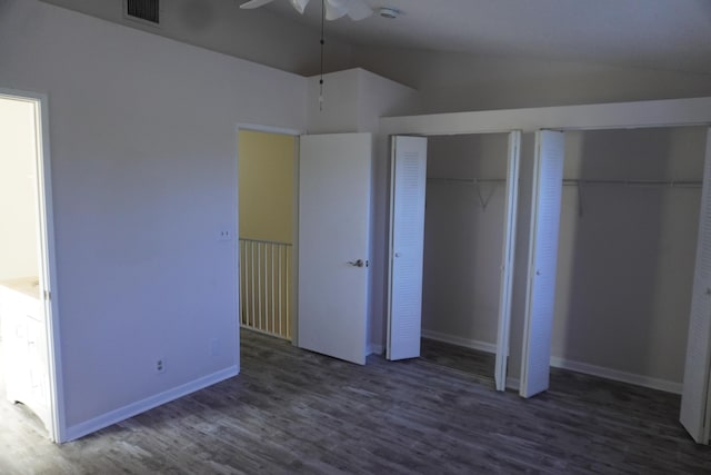 unfurnished bedroom featuring ceiling fan, two closets, dark wood-type flooring, and lofted ceiling