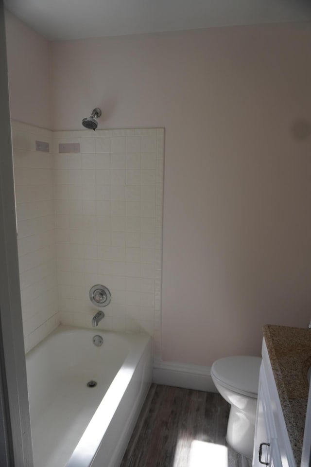 full bathroom with tiled shower / bath combo, toilet, wood-type flooring, and vanity