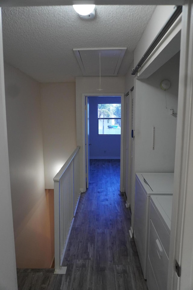 hallway featuring dark hardwood / wood-style flooring, a textured ceiling, and washing machine and clothes dryer