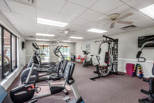 gym featuring ceiling fan and a drop ceiling