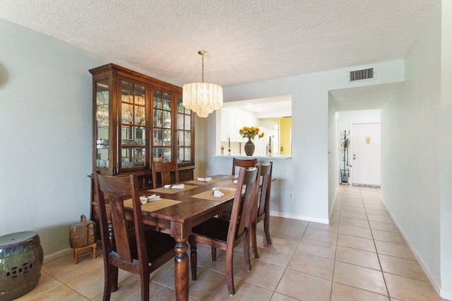 tiled dining area with a notable chandelier and a textured ceiling