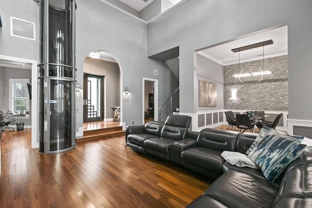 home theater room featuring hardwood / wood-style floors, a towering ceiling, and crown molding