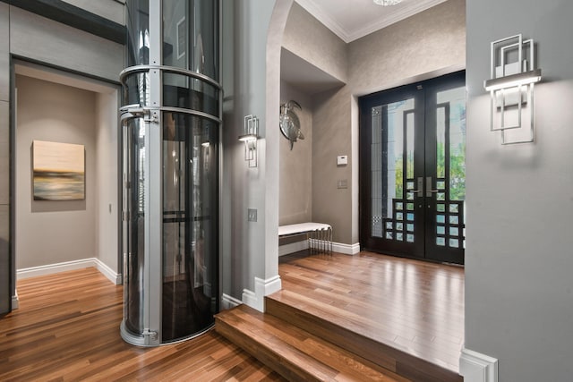 foyer featuring hardwood / wood-style floors, crown molding, and french doors