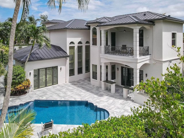 back of property featuring ceiling fan, a patio area, and a balcony