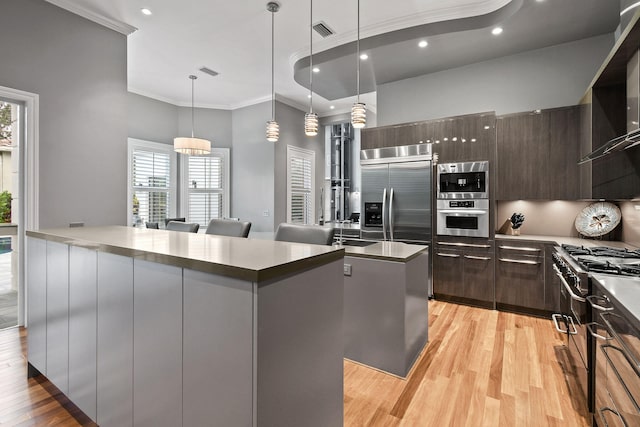 kitchen featuring a wealth of natural light, light wood-type flooring, and hanging light fixtures