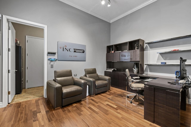 office featuring a high ceiling, light wood-type flooring, and ornamental molding