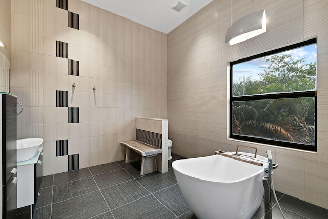 bathroom featuring a tub, tile walls, and toilet