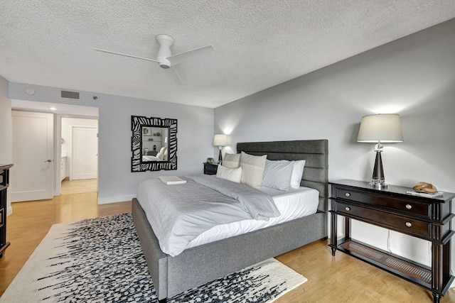 bedroom featuring light hardwood / wood-style flooring, ceiling fan, and a textured ceiling