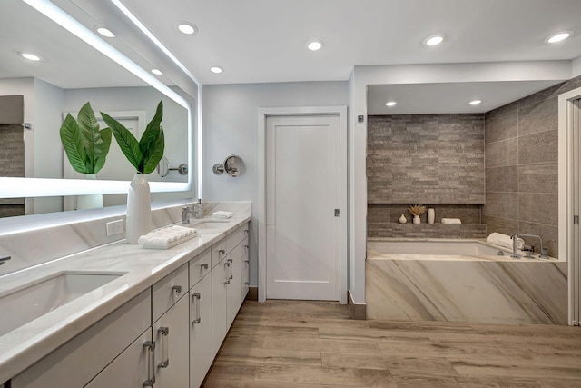 bathroom with a bath, hardwood / wood-style floors, and vanity