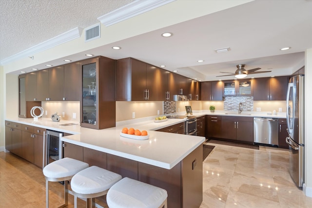 kitchen featuring kitchen peninsula, appliances with stainless steel finishes, a breakfast bar, and ornamental molding