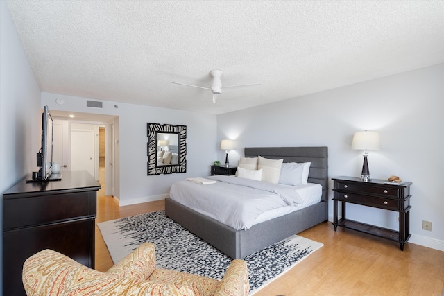 bedroom featuring ceiling fan, light hardwood / wood-style floors, and a textured ceiling