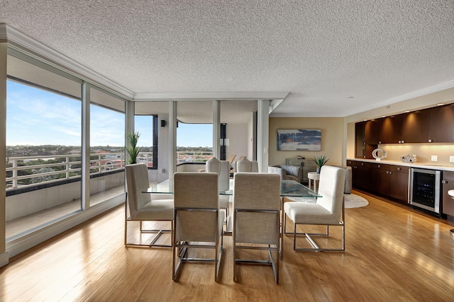 dining room featuring wine cooler, light hardwood / wood-style flooring, expansive windows, and a textured ceiling