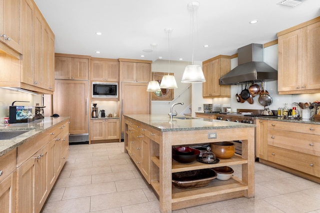 kitchen with high end range, wall chimney exhaust hood, built in microwave, sink, and pendant lighting