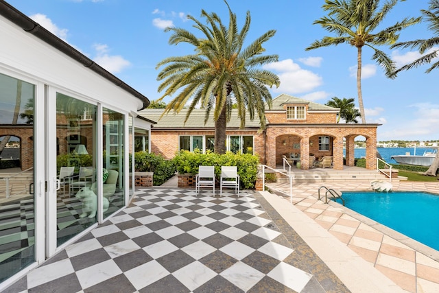 view of swimming pool featuring a patio area and a water view