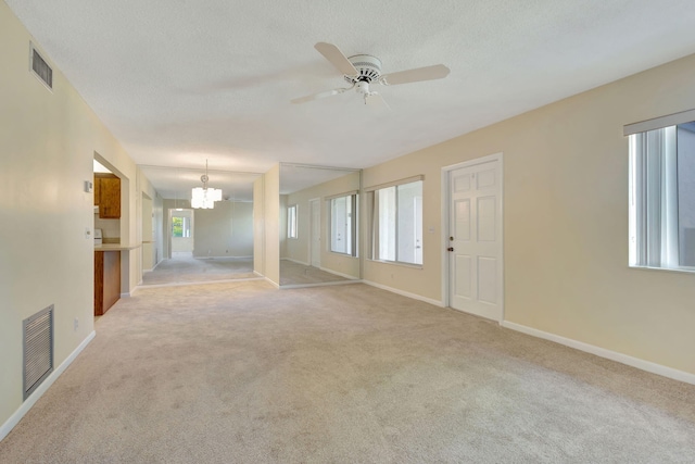 unfurnished room featuring carpet, ceiling fan with notable chandelier, and a textured ceiling