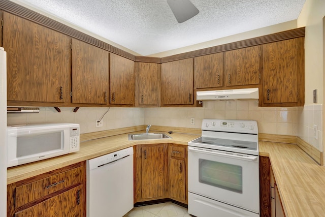 kitchen featuring a textured ceiling, white appliances, butcher block countertops, and sink