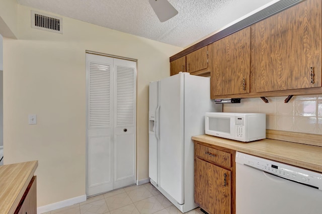 kitchen with a textured ceiling, white appliances, and ceiling fan