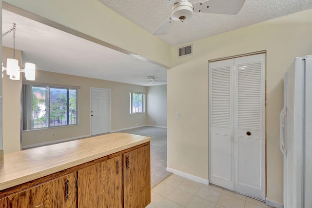 kitchen featuring a healthy amount of sunlight, ceiling fan with notable chandelier, hanging light fixtures, and white fridge with ice dispenser