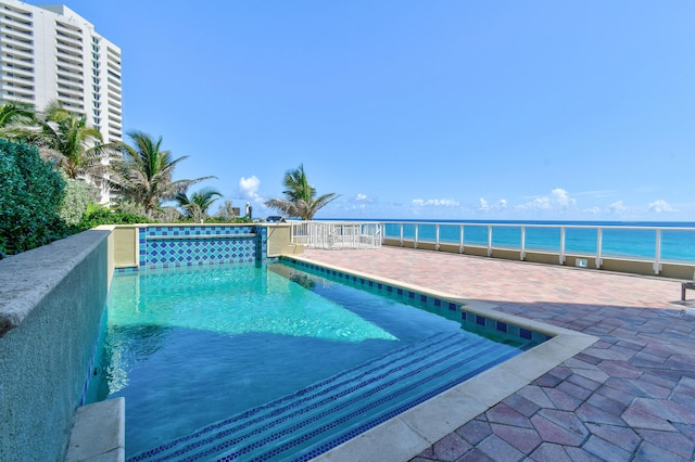 view of pool with a water view and a patio