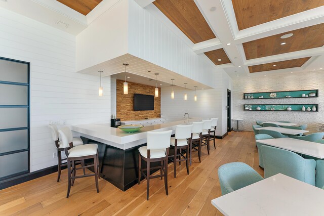 kitchen with coffered ceiling, a breakfast bar, hanging light fixtures, beamed ceiling, and a high ceiling