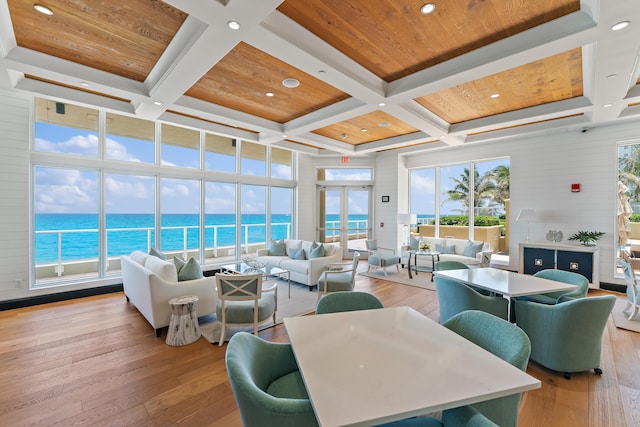 living room with coffered ceiling, wood ceiling, a water view, beam ceiling, and light hardwood / wood-style flooring